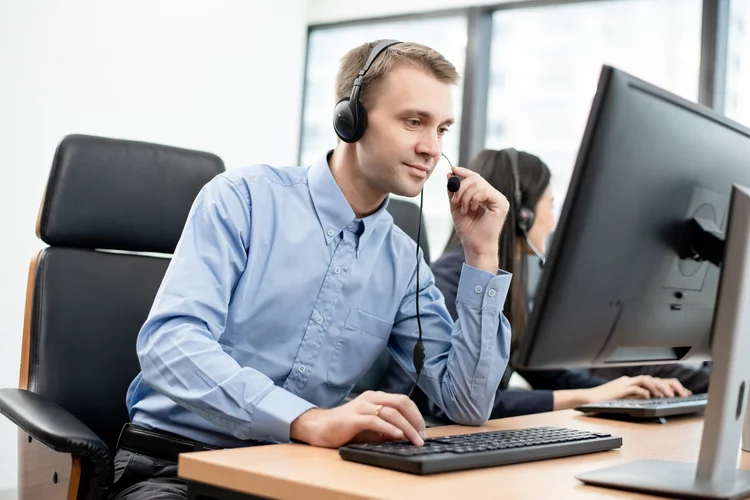 IT support specialist wearing a headset while working at a desktop computer