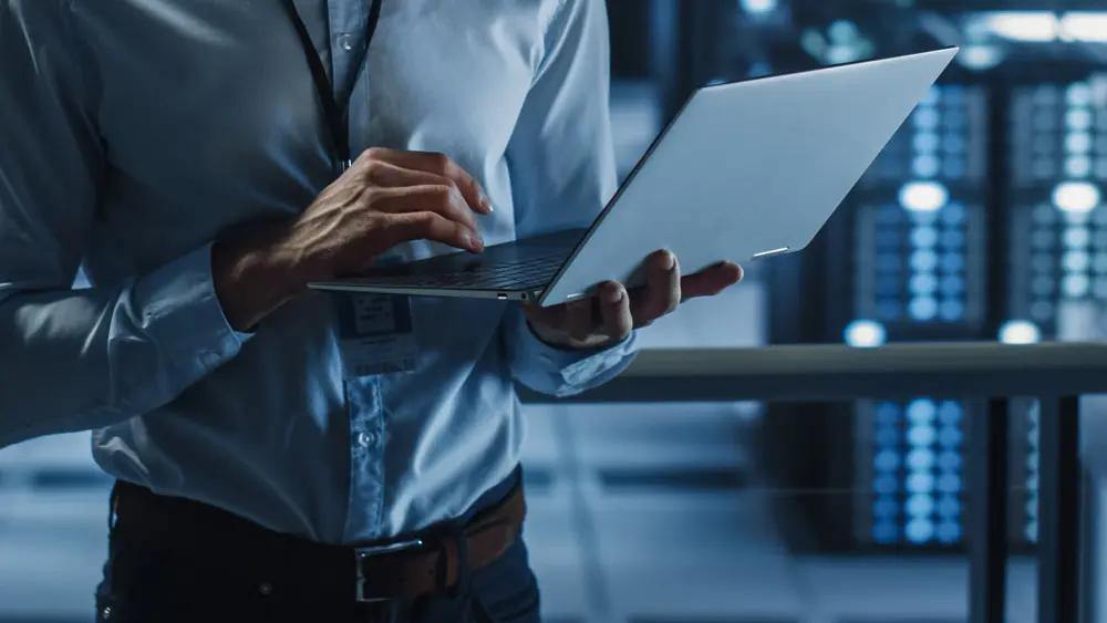 IT professional managing a business laptop near data center infrastructure