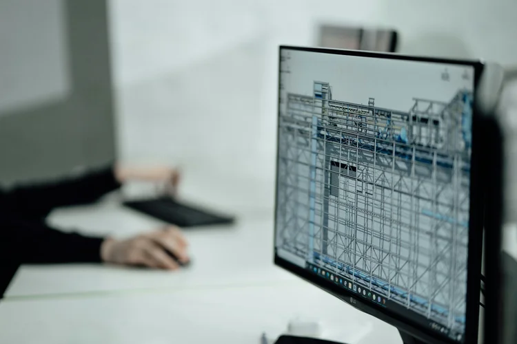 Computer monitor displaying a detailed technical design in an office